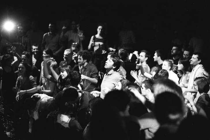 Photographie en noir et blanc d'une des scènes de l'Opéra Underground. On peut voir plusieurs personnes (environ une trentaine) en train de danser.